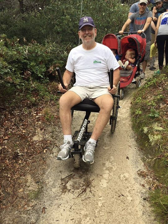 Configuring the GRIT Freedom Chair for Taller Riders: Ken lengthens legs on steering pegs over front GRIT mountainboard wheel on family hike