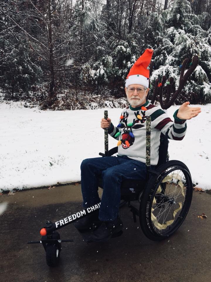 How Easy Is GRIT Freedom Chair To Push or Use for Seniors: John waves a hand using GRIT Freedom Chair offroad wheelchair in snow on pavement