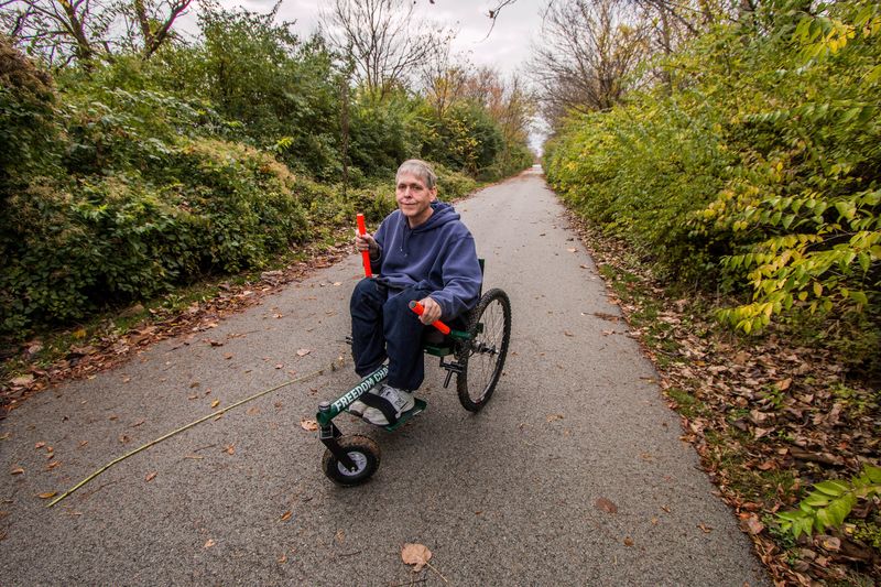 Getting to Know My GRIT Freedom Chair First GRIT Adventure: Brad on paved trail through greenery and leaves using new all-terrain wheelchair
