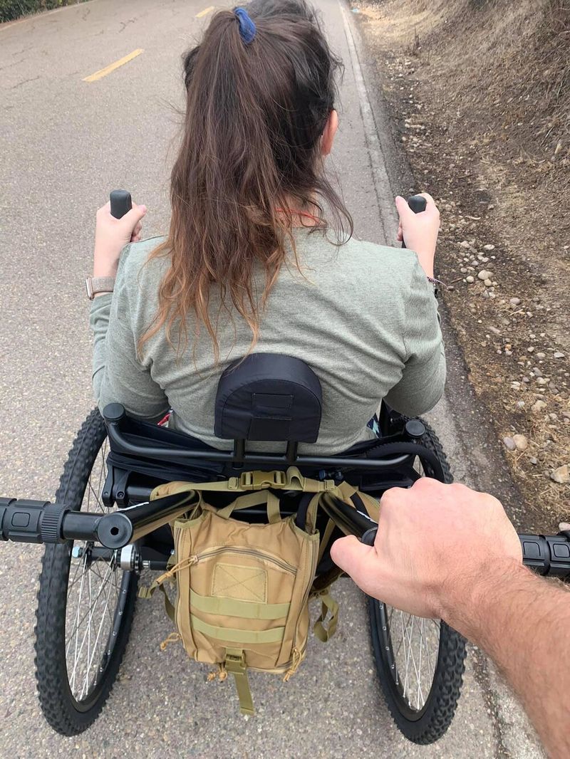 Independence and assistance how to choose all-terrain wheelchair: person pushing another in GRIT Freedom Chair using trail handles