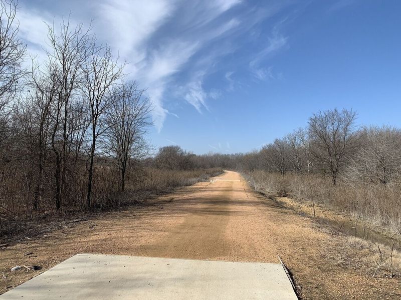 Accessible Hiking Trails You’ve Never Heard Of, Little Elm Lakefront Trail in TX: paved area into dirt path through bare trees in Texas