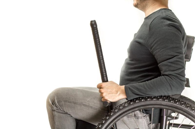 Science the Secret Behind GRIT Freedom Chair, leveraging physics: person in off-road wheelchair holding bottoms of levers
