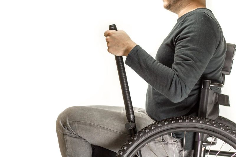 Science the Secret Behind GRIT Freedom Chair, leveraging physics: person in off-road wheelchair holding tops of levers