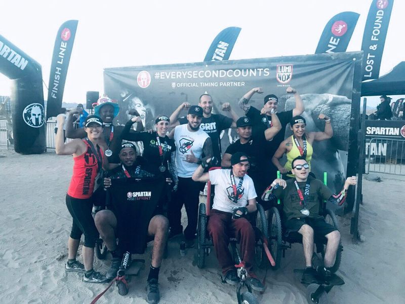 Trandon Mechling: Spartan, GRIT Athlete: a group of 11 Spartan athletes, including 3 in GRIT Freedom Chairs, flex at race finish line