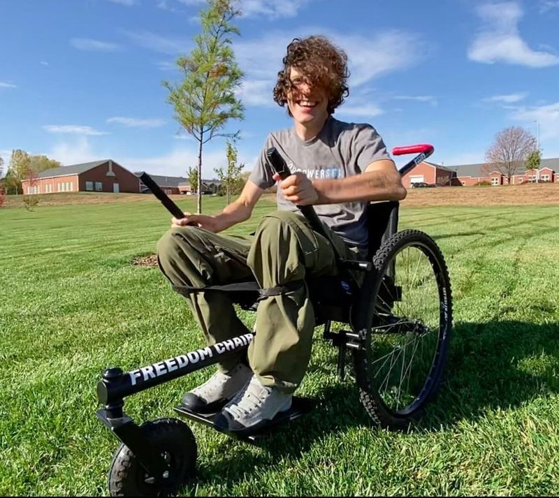 Versatility how to choose all-terrain wheelchair: person riding GRIT Freedom Chair on grass smiling